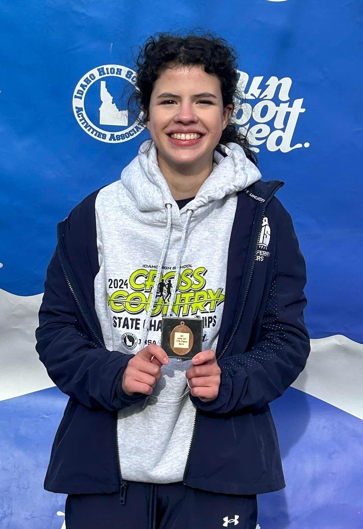 Bonners Ferry High senior Sydney Beckle shows off the medal she received for finishing 17th at the 4A state championship this year.