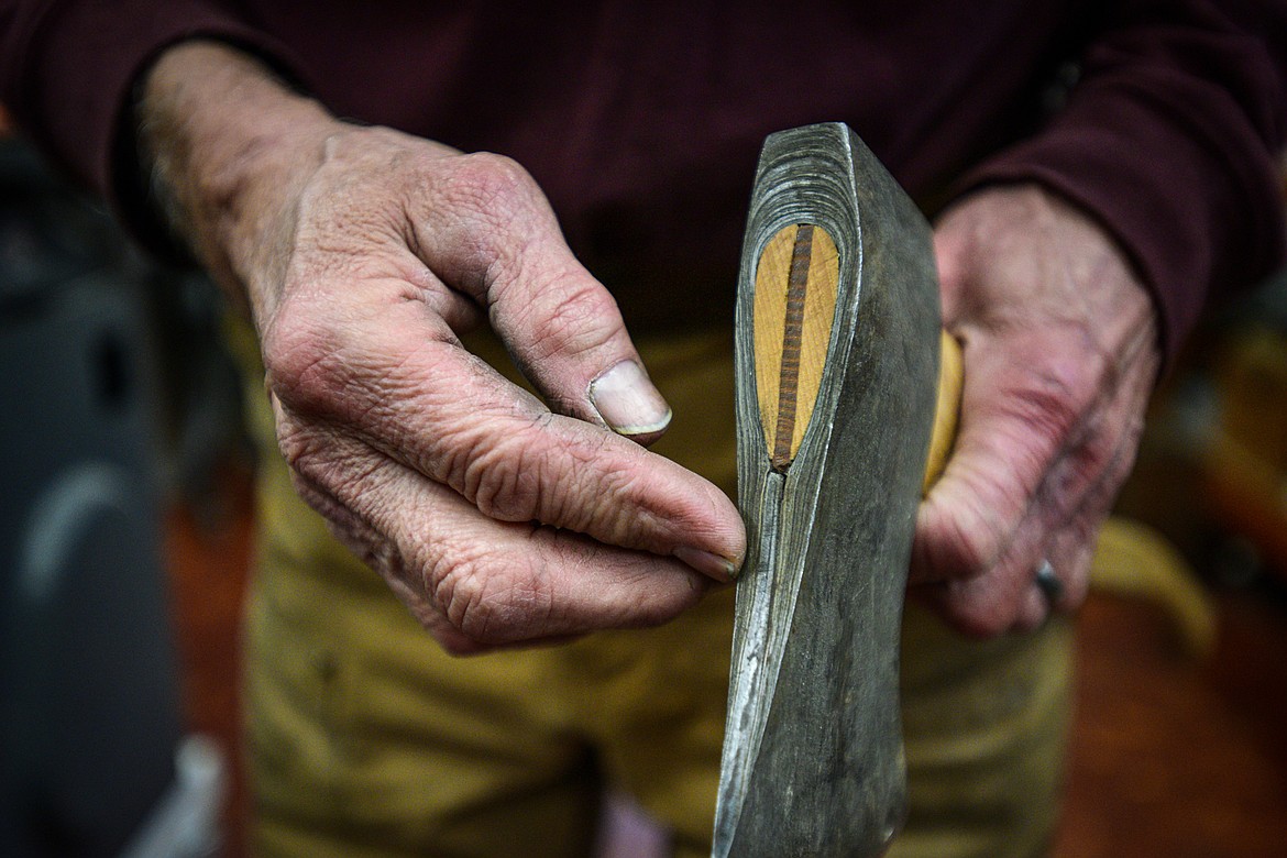 Jeffrey Funk shows a piece of steel repurposed from an automobile leaf spring inside an axe head that was forged from iron salvaged from the Old Steel Bridge in Evergreen. (Casey Kreider/Daily Inter Lake)