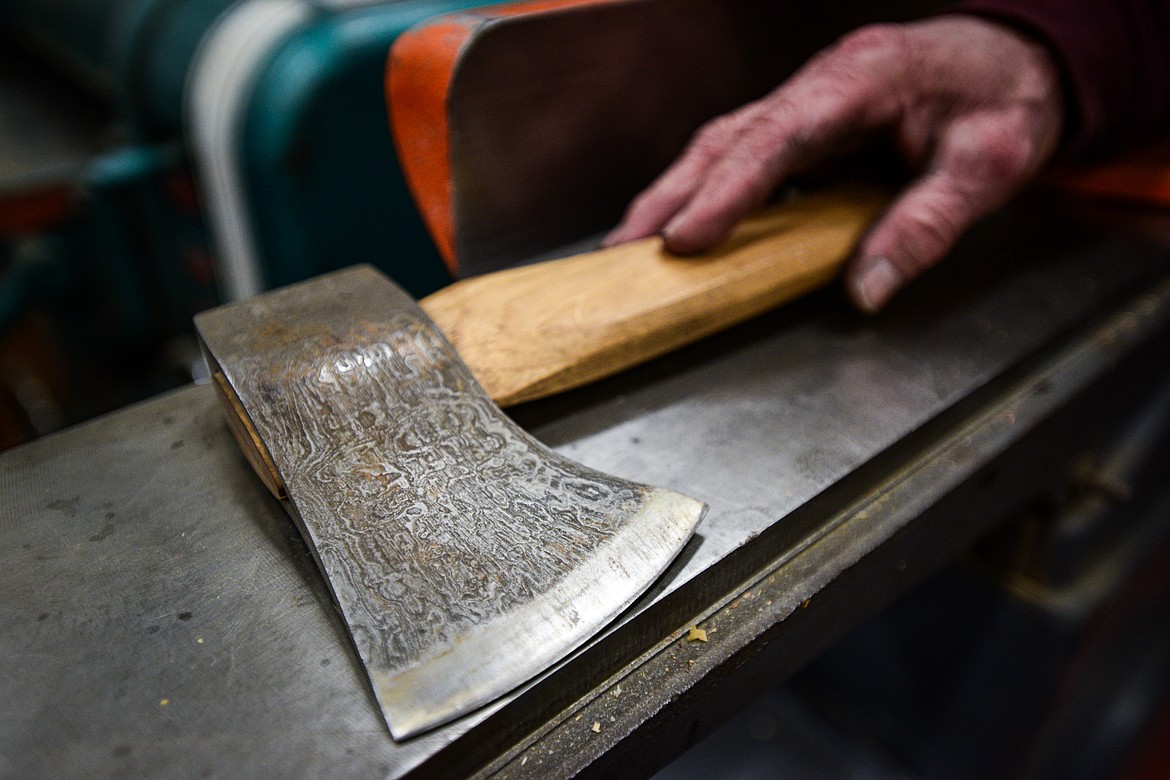 Jeffrey Funk shows an axe inside his workshop that was forged from iron salvaged from the Old Steel Bridge that used to span the Flathead River in Evergreen. The grain is created by etching the axe head in acid, dissolving out the slag in the wrought iron from the bridge.