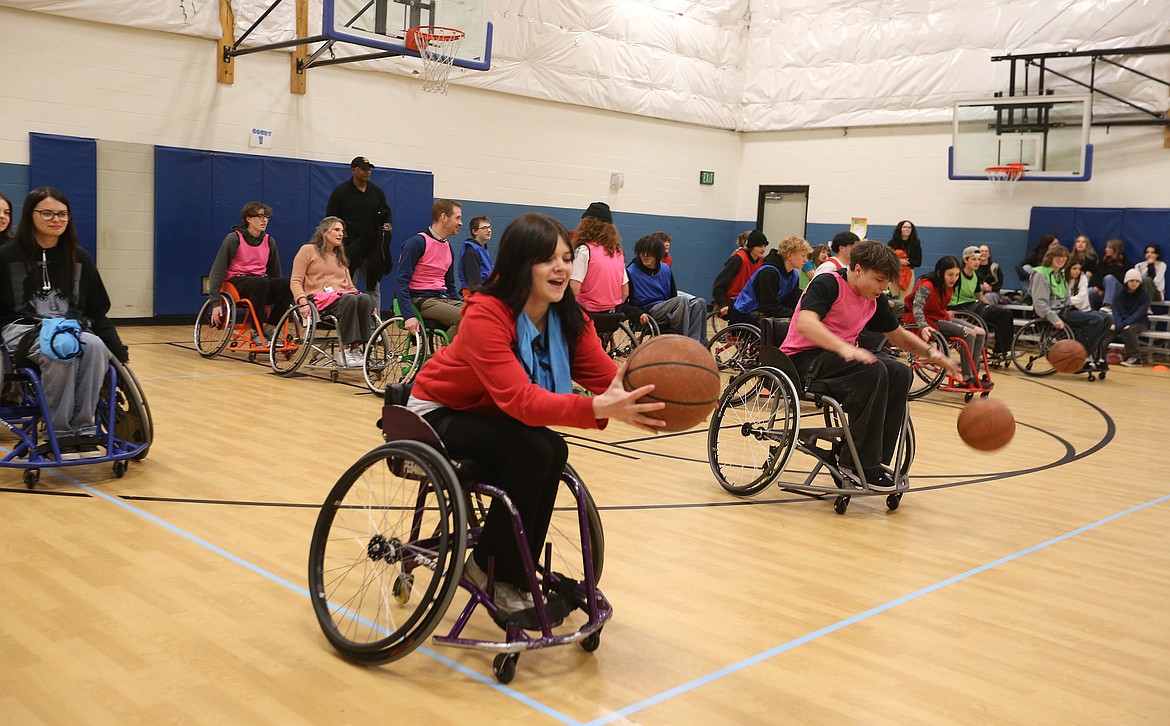 Sophomore Scarlet Haines tries to dribble while moving down court in a basketball wheelchair Wednesday as New Vision High students work with Paralympic champs at the Boys and Girls Club in Post Falls.