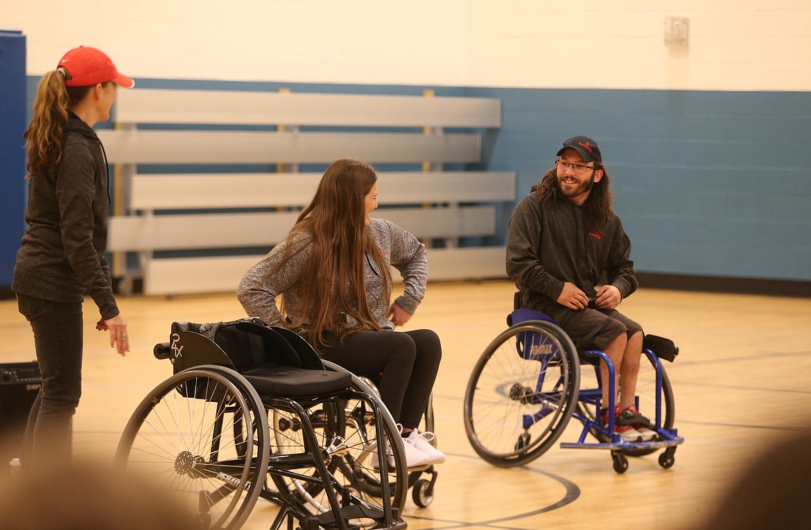 From left, ParaSport Spokane founder Teresa Skinner and Paralympians Chelsea McClammer and Isaiah Rigo discuss specialized wheelchairs for adaptive sports Wednesday before inviting New Vision students to join them on the floor.