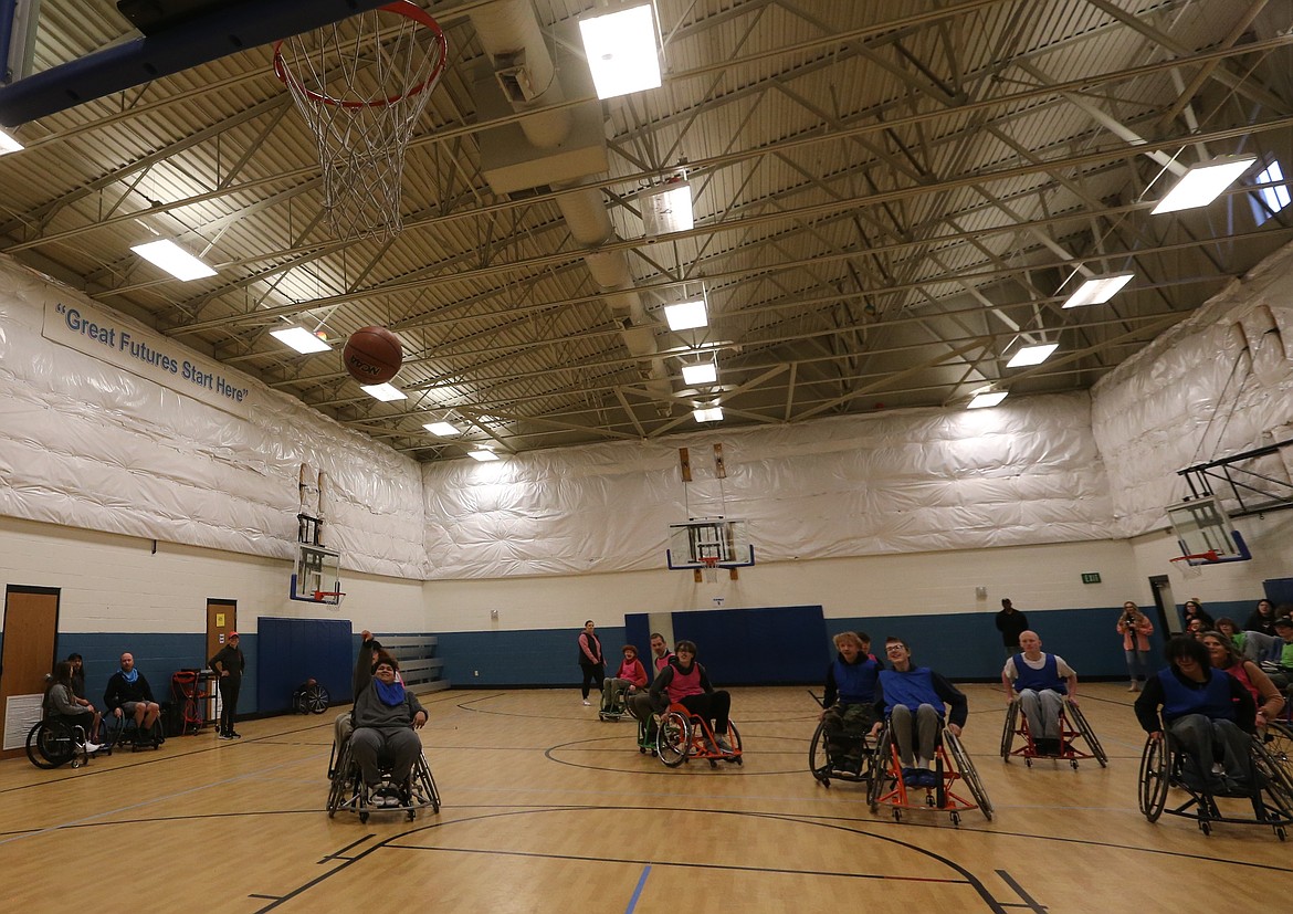 Senior Chuy Soto, left, shoots for a hoop from a specialized basketball wheelchair Wednesday as his schoolmates cheer him on.