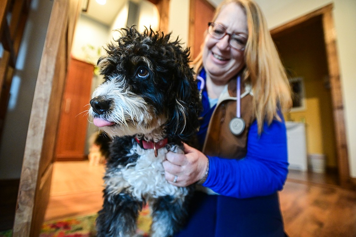 Mr. Snifferton takes a break from greeting clients to receive some scratches and treats from Wendy Gordon, Clinical Care Coordinator, at Bluebird Health Imaging in Kalispell on Thursday, Nov. 14. (Casey Kreider/Daily Inter Lake)