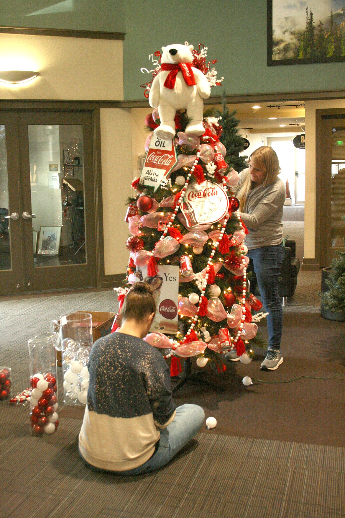 Kayla Hoffer (seated) and Anna Lucero (standing) decorate a tree for a previous Habitat for Humanity of Greater Moses Lake Festival of Trees.