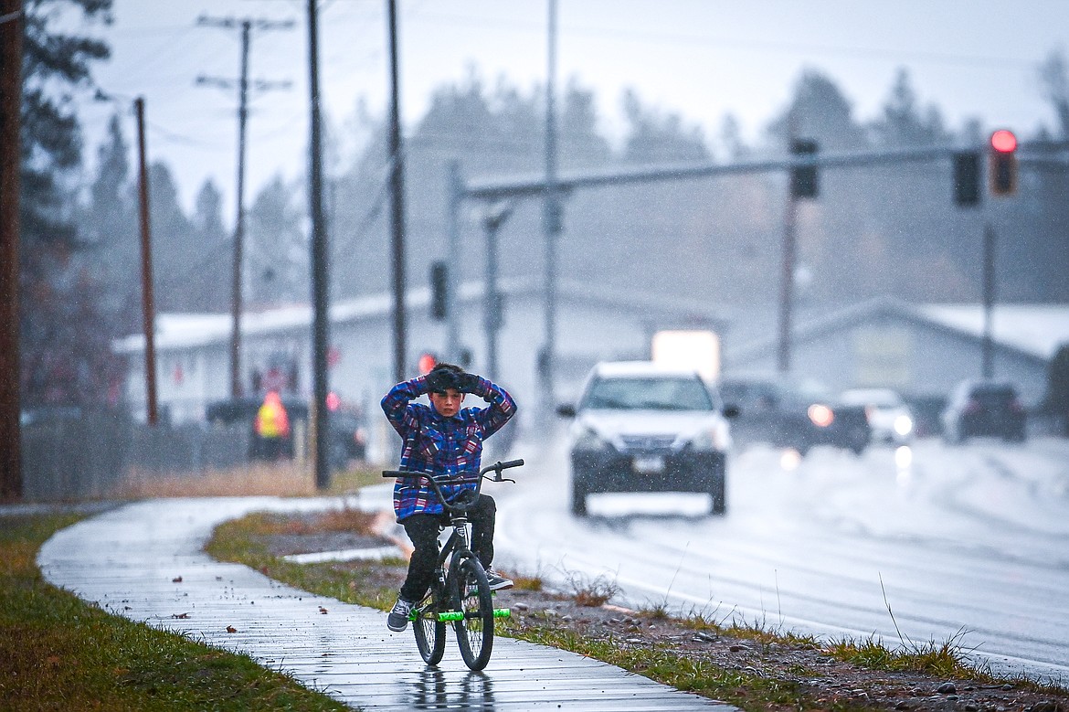 A boy pedals a bicycle along the sidewalk on U.S. Highway 2 in Evergreen on Thursday, Nov. 14. (Casey Kreider/Daily Inter Lake)