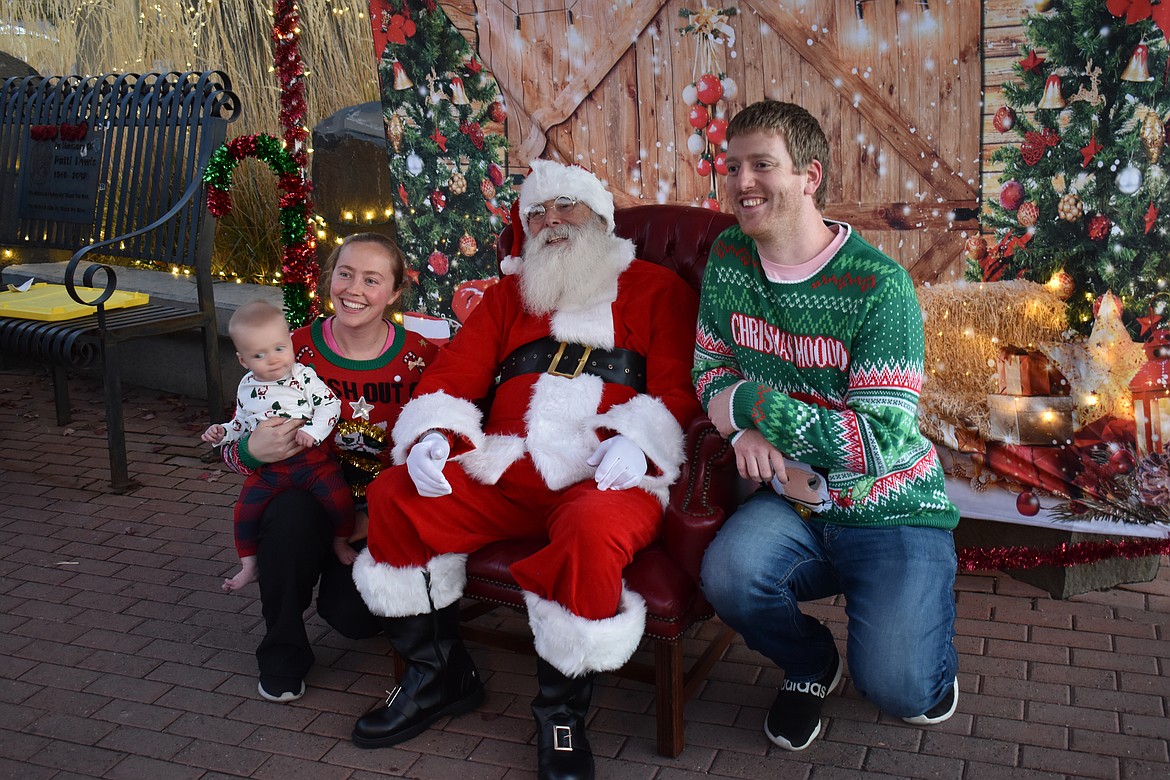 Karlson Keel, right, and Cheyenne Griffith, clad in magnificently garish Christmas sweaters, share a photo with Santa and their son Harrison Keel, 7 months.