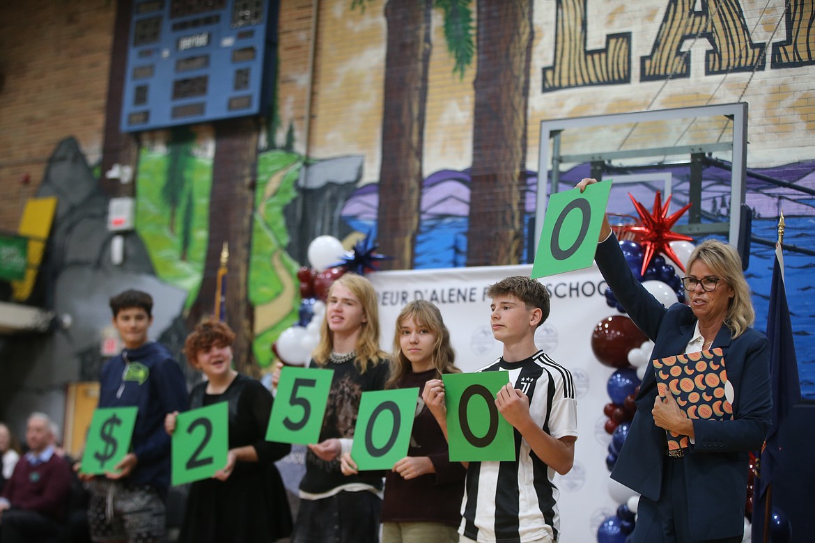 Idaho Superintendent of Public Instruction Debbie Critchfield adds a zero Wednesday morning as some of Lakes Middle School math teacher Marcus Ross' students hold up numbers to reveal the amount of Ross' cash prize. He won $25,000 as well as the Milken Educator Award.