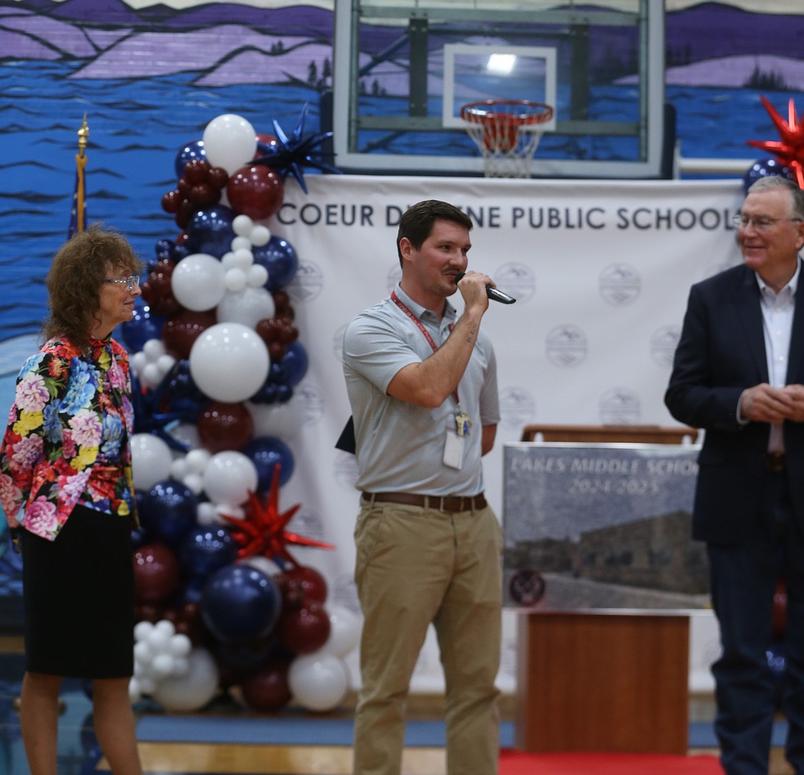 Flanked by Milken Educator Awards Senior Vice President Jane Foley and Idaho Lt. Gov. Scott Bedke, Lakes eighth grade math teacher Marcus Ross addresses the crowd Wednesday after learning he is a 2024 recipient of the Milken Educator Award.