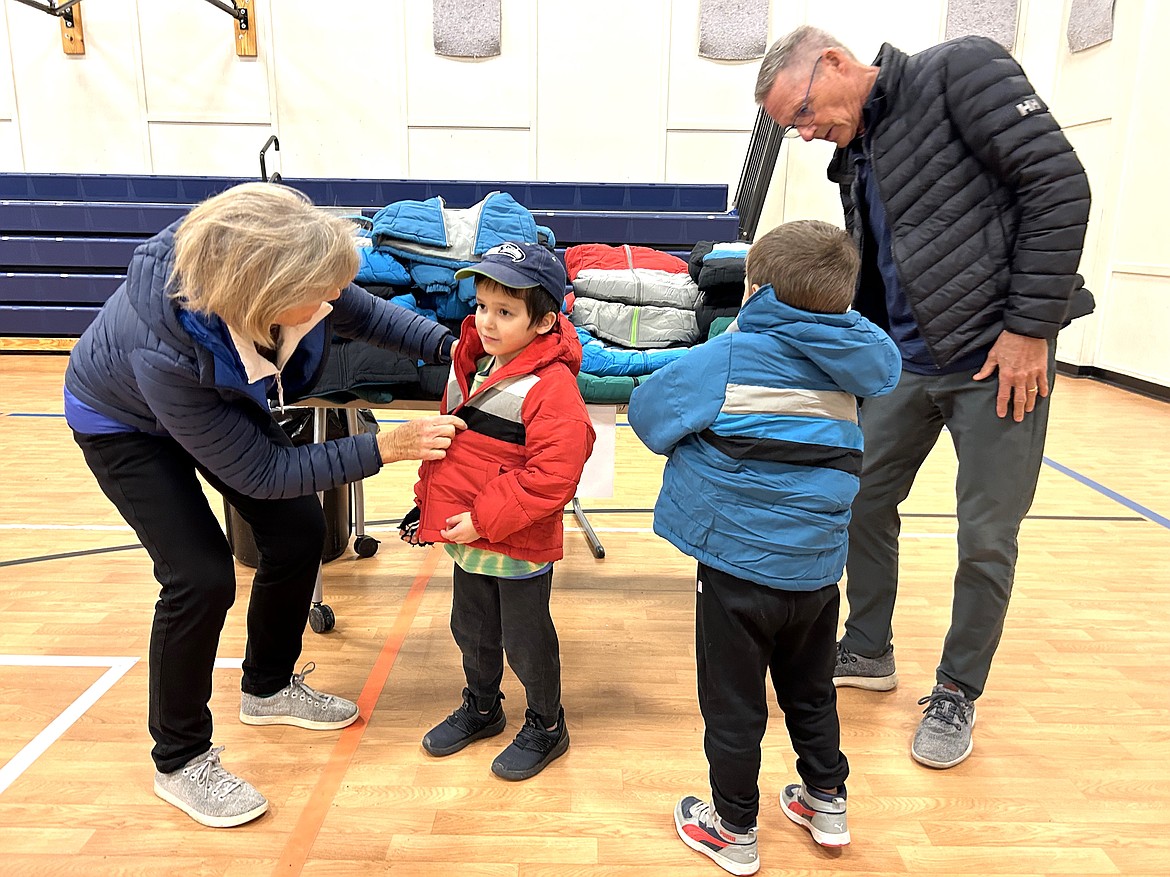 Volunteers Brad and Janice Baldwin help two boys try on coats at the Kootenai County Boys and Girls Club on Thursday.