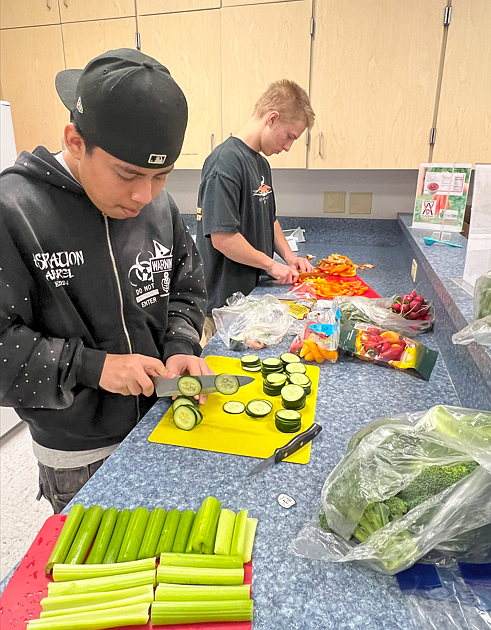 Juniors Kevin Lindelof, right, and Jose Barragan Reyes on Wednesday team up to cut vegetables that were paired with the Eat Smart Idaho hummus recipe for Venture Academy’s exhibit night.