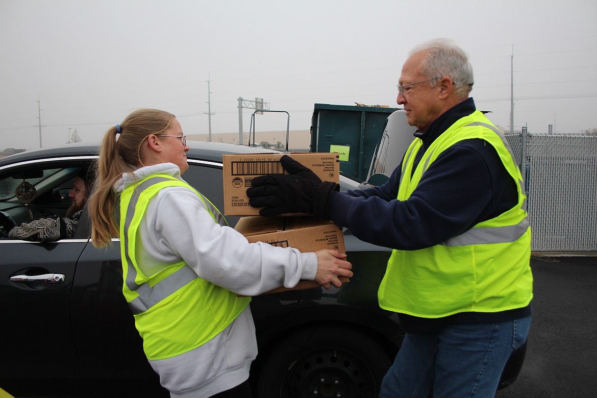 Jamie Wolfe, left, and Marcus Anderson, right, load potatoes for a food bank client.