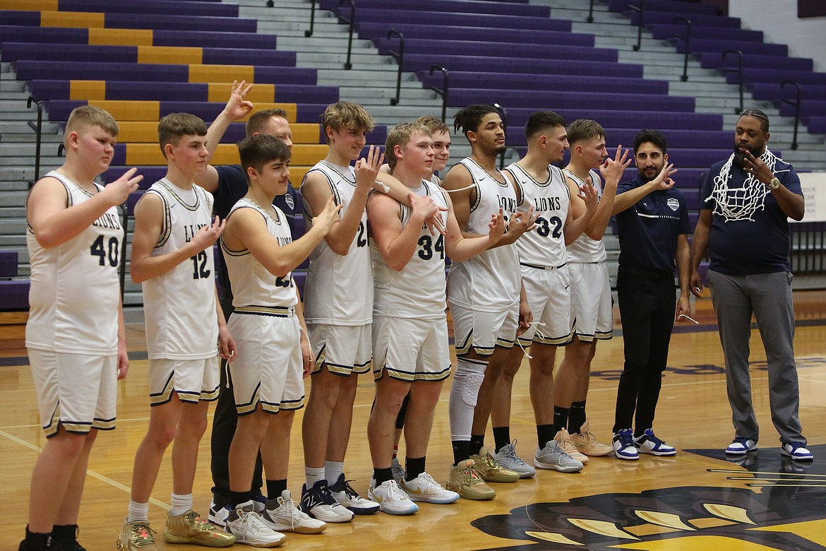 Lion players celebrate by holding up three fingers after winning their third straight Central Washington B district tournament last February.