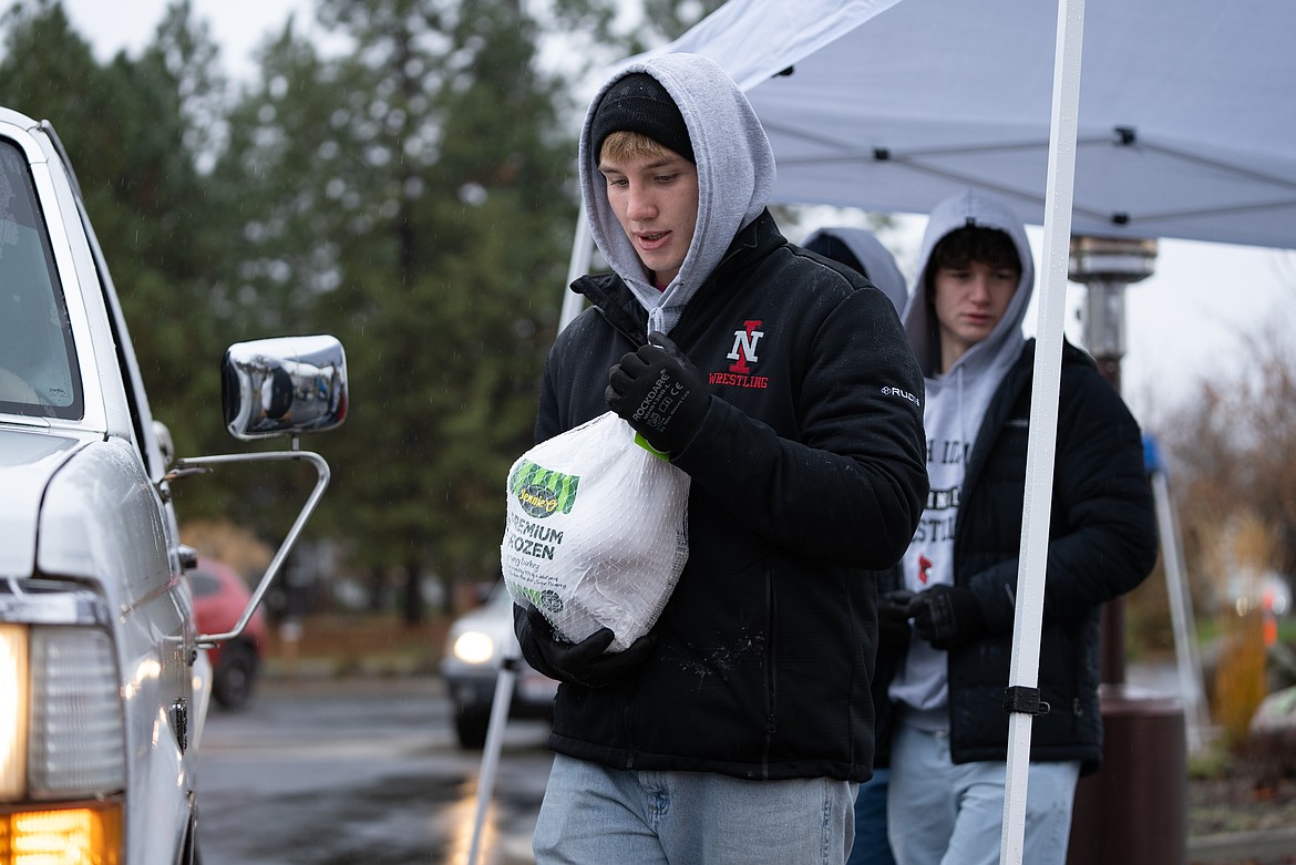 NIC ATHLETICS
Dylan Block prepares to give out a frozen turkey during a Turkeys and More drive-thru event at Unity Church in Coeur d’Alene.