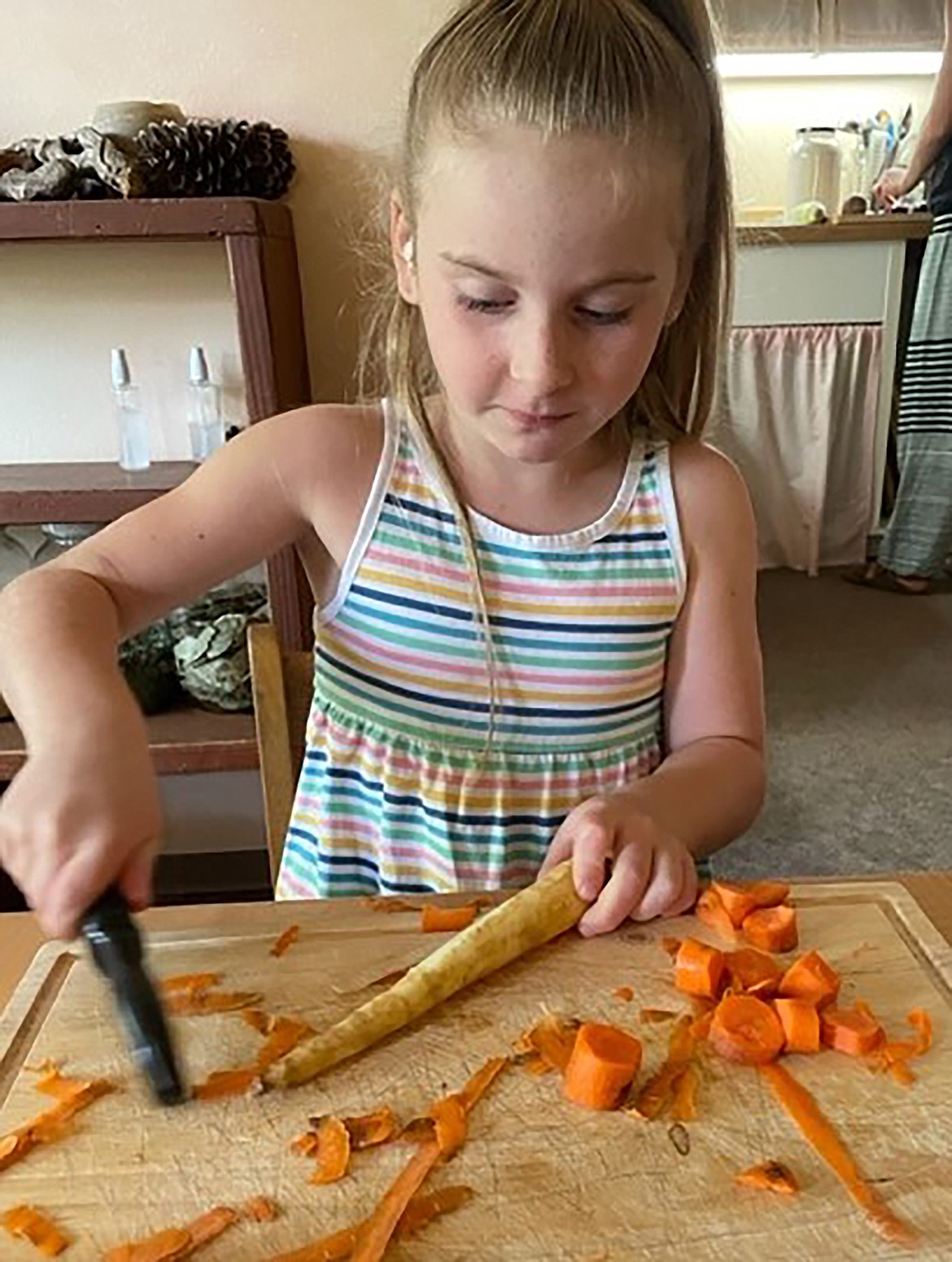 A kindergarten student peels vegetables for soup making at Sandpoint Waldorf School