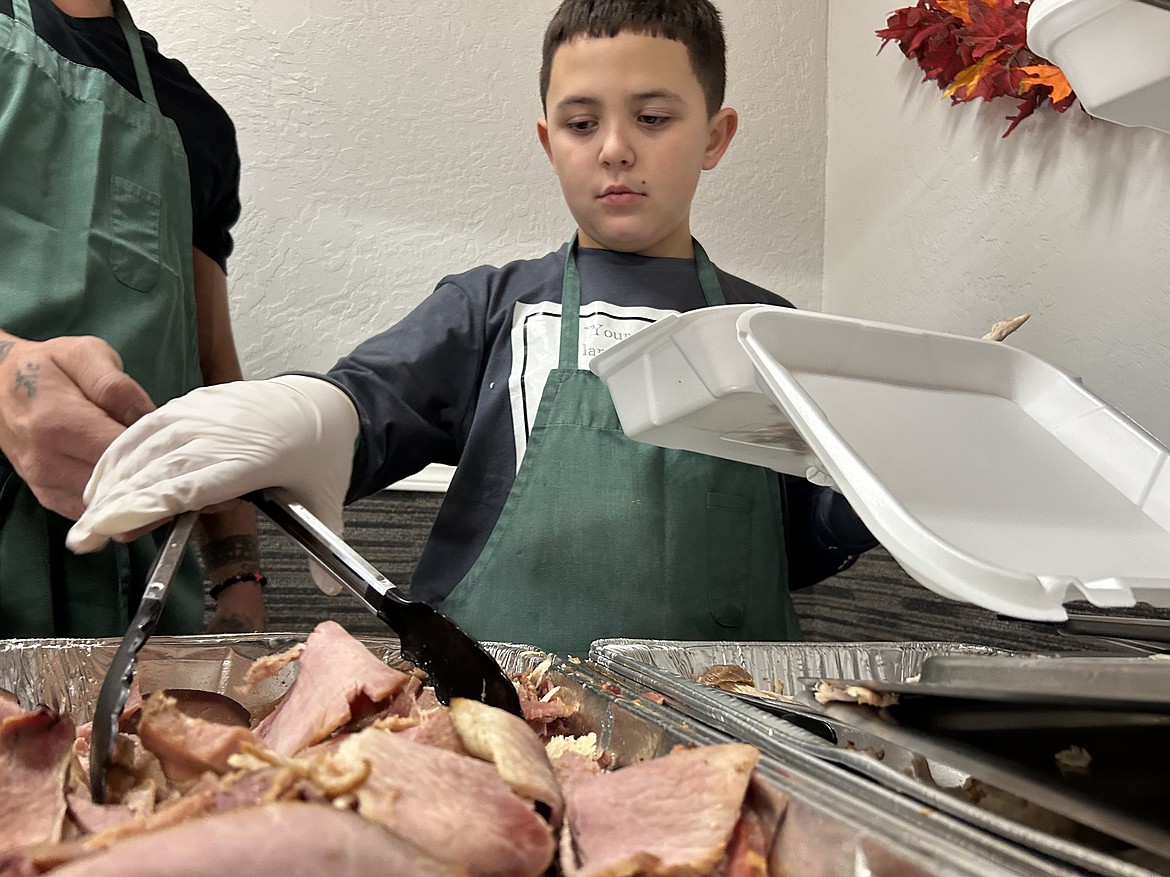 Isaiah Antoine Childers, 9, serves ham on Thanksgiving at The Altar Church.