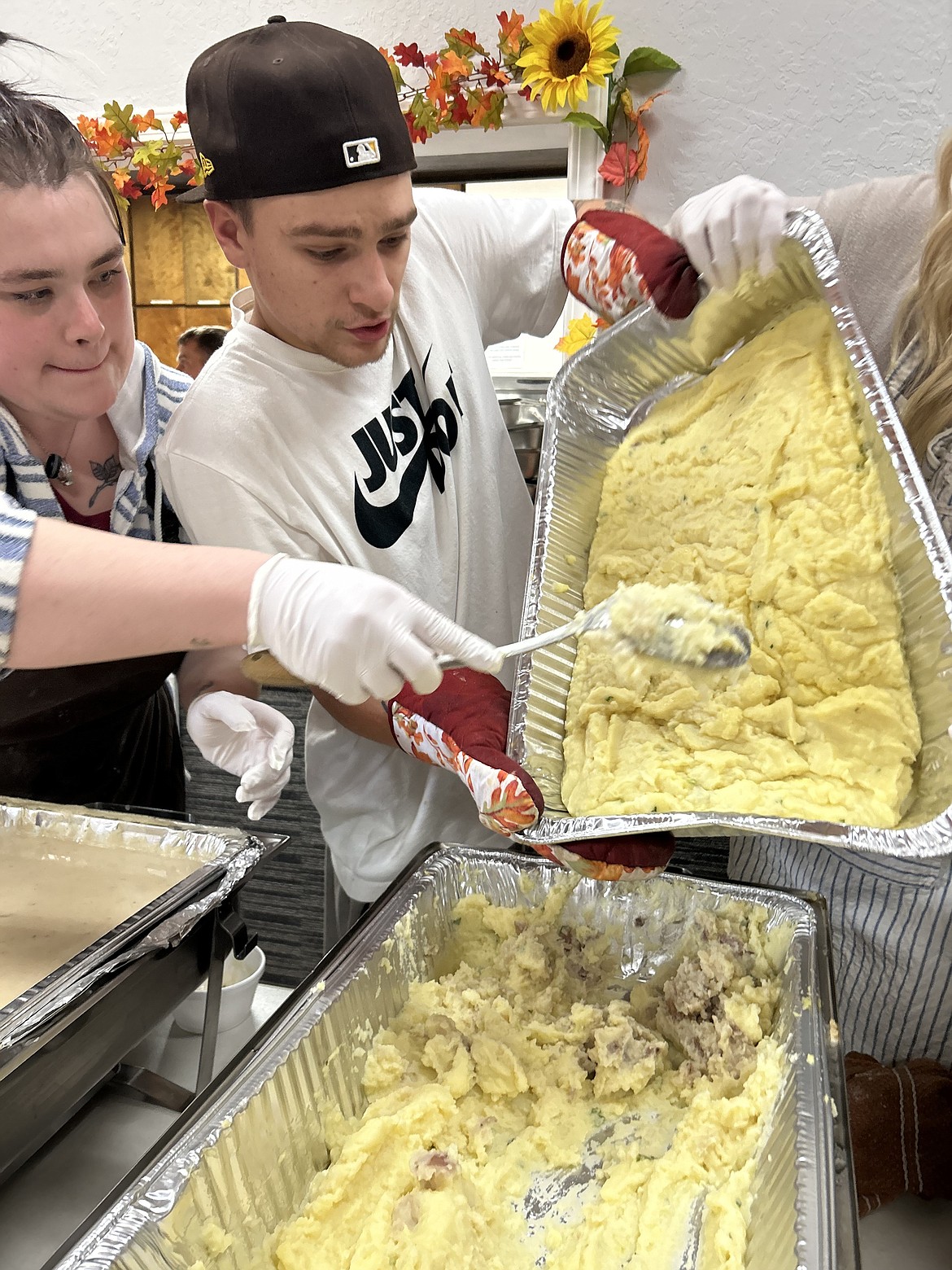 Jon Lun, with help from Brooke Wagner, pours out more mashed potatoes on Thanksgiving at The Altar Church.