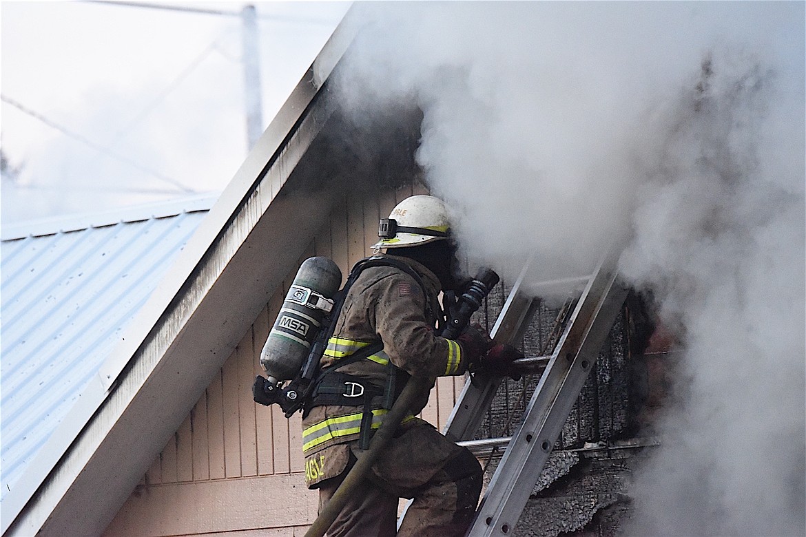 Libby Volunteer Fire Department First Assistant Fire Chief Scott Beagle climbs a ladder at the scene of a house fire at the corner of California Avenue and West Spruce Street in Libby Sunday, Dec. 1, 2024. (Scott Shindledecker/The Western News)