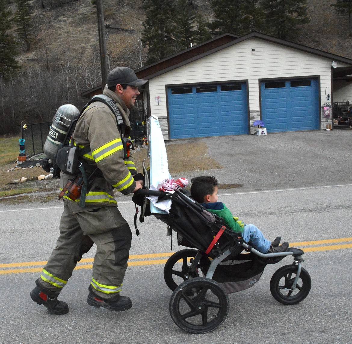 Deputy Chief of the Superior Volunteer Fire Department, Josh Pecora, ran in his hefty firefighting gear while pushing his son Mason. (Mineral Independent/Amy Quinlivan)