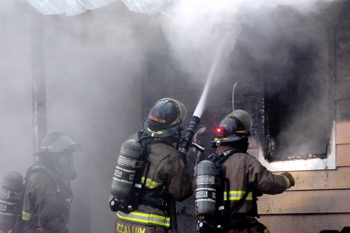 Libby Volunteer Fire Department's Kevin McCallum sprays water on a house fire Sunday, Dec. 1, 2024, at the corner of California Avenue and West Spruce Street in Libby. (Scott Shindledecker/The Western News)