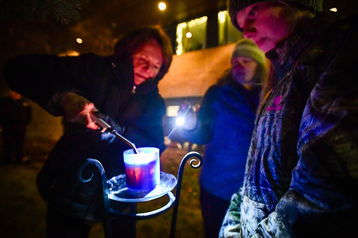 Sandi Waverck lights a "Never Forget" candle during the Blue Light Christmas Tree Lighting ceremony outside the Flathead County Justice Center in Kalispell on Tuesday, Dec. 3. The event is held in support of the families of fallen officers and to honor the officers, firefighters, first responders and all those who serve and protect. (Casey Kreider/Daily Inter Lake)