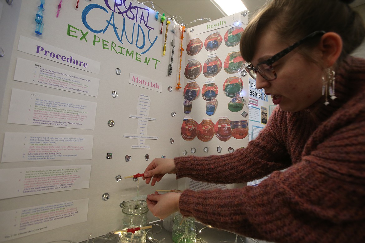 University of Idaho student Ava Mendoza demonstrates how sugar crystals formed in different sizes of mason jars Dec. 3 during her elementary education class science fair at North Idaho College.