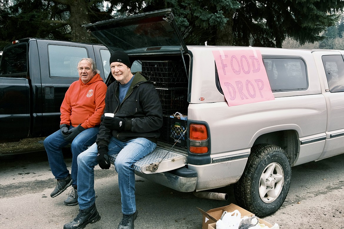 Volunteers Timmy D. and John Birrell break from loading food donations into a pickup truck.