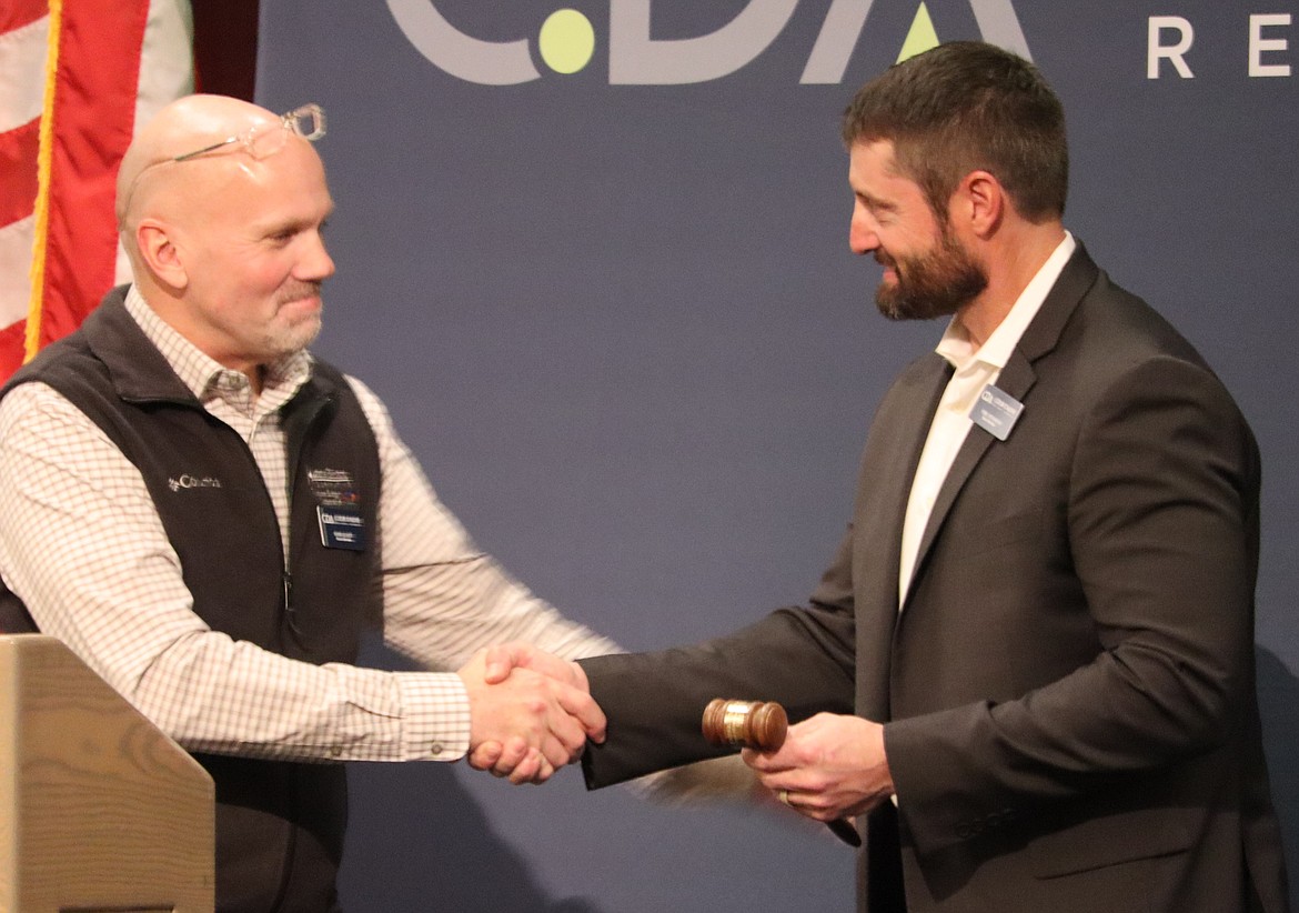 Doug Elliott, outgoing chair of The Coeur d'Alene Regional Chamber, hands the gavel to incoming chair Tyrel Stevenson on Wednesday.