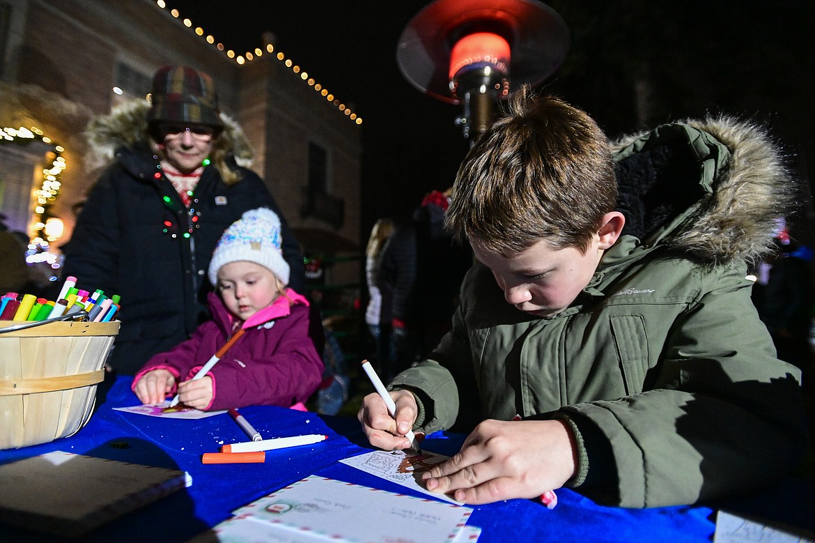 Kids write letters to Santa Claus outside Johnson-Gloschat Funeral Home and Crematory at the Downtown Holiday Stroll & Tree Lighting Ceremony on Friday, Dec. 6. (Casey Kreider/Daily Inter Lake)