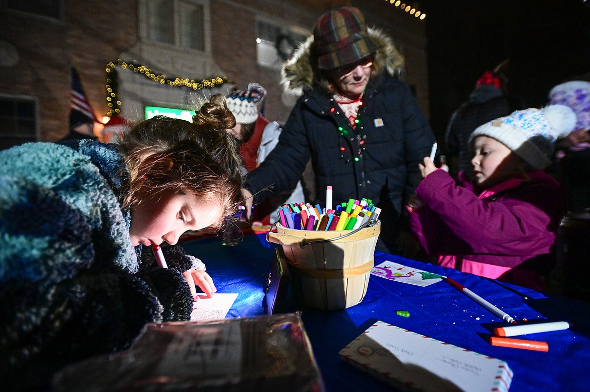 Kids write letters to Santa Claus outside Johnson-Gloschat Funeral Home and Crematory at the Downtown Holiday Stroll & Tree Lighting Ceremony on Friday, Dec. 6. (Casey Kreider/Daily Inter Lake)