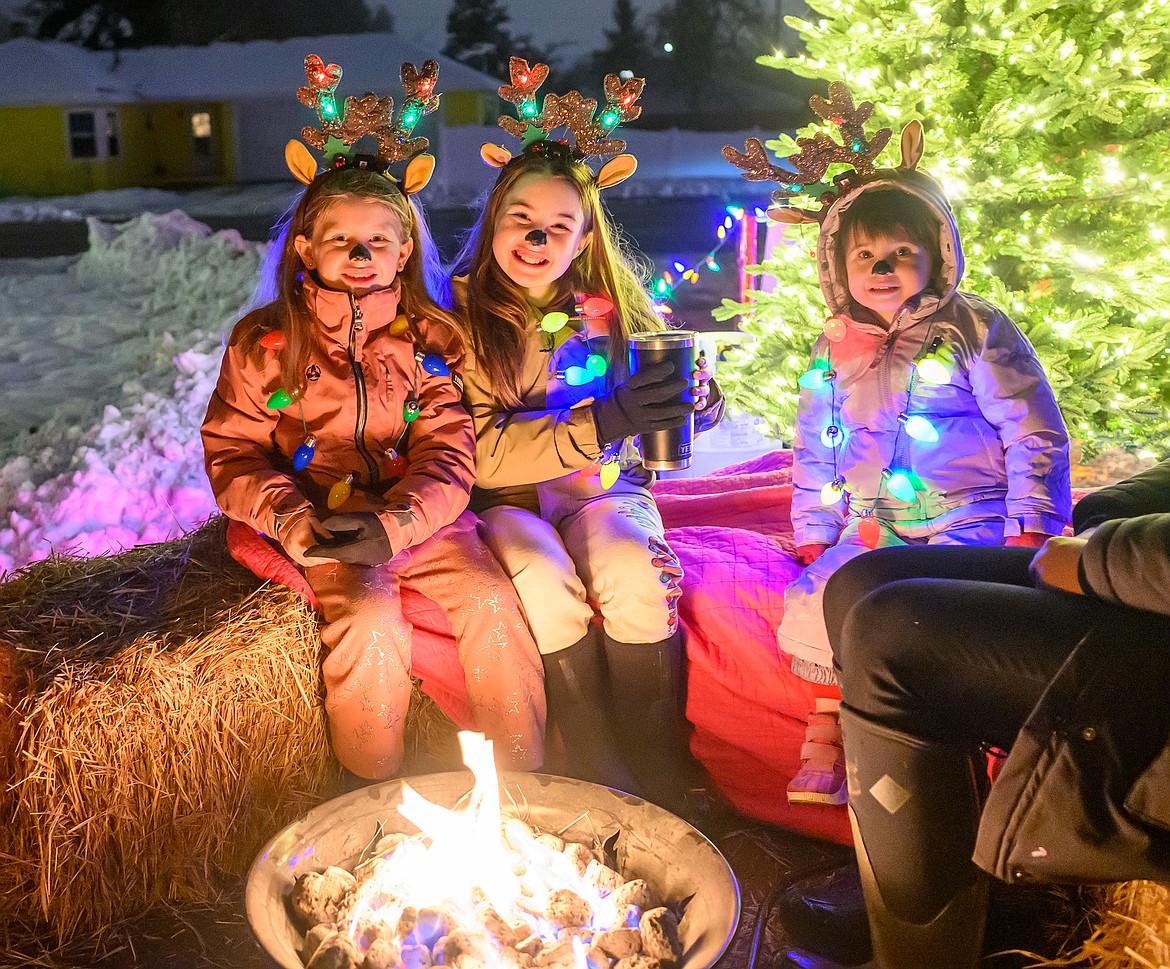 Finley Butcher, Rosella Groschupf  and her younger sister Hazel keep warm before the parade starts.