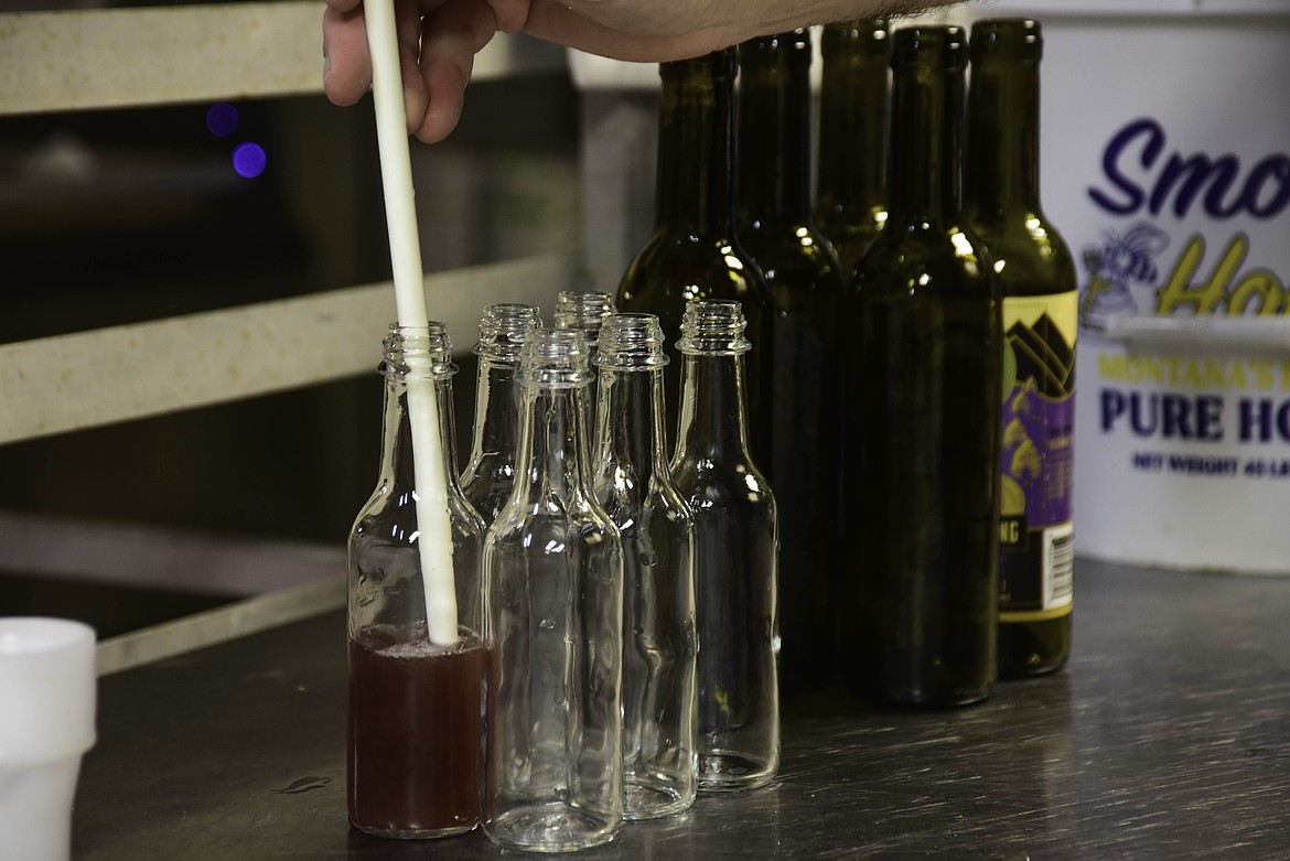 Doug Satterly fills a small bottle of Mountain Home Meadworks syrup on Dec. 10, 2024. (Kate Heston/Daily Inter Lake)