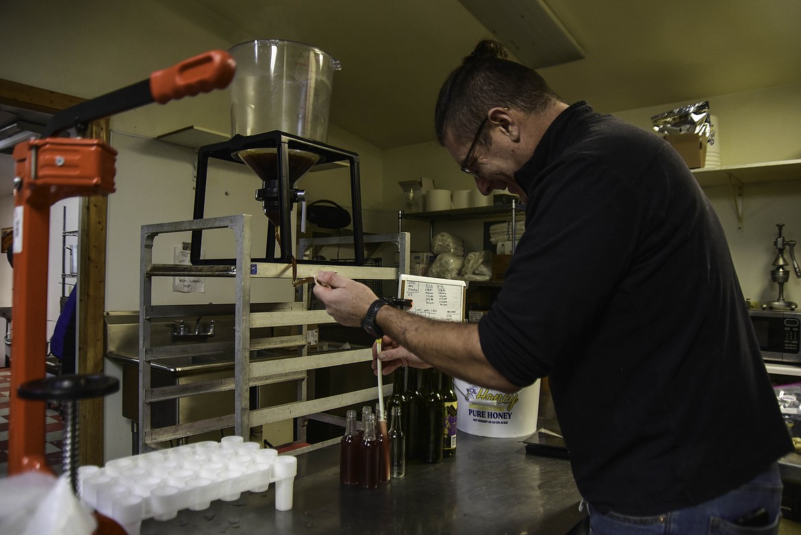 Doug Satterly fills a small bottle of Mountain Home Meadworks syrup on Dec. 10, 2024. (Kate Heston/Daily Inter Lake)