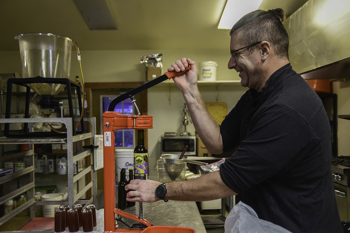 Doug Satterly corks a large bottle of Mountain Home Meadworks syrup on Dec. 10, 2024. (Kate Heston/Daily Inter Lake)