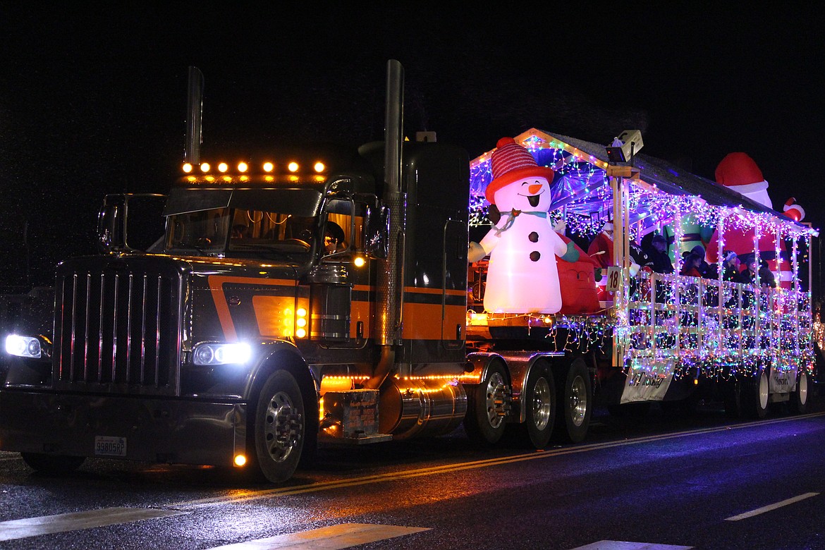 A truck and wagon decked out in holiday lights make their way down the parade route.