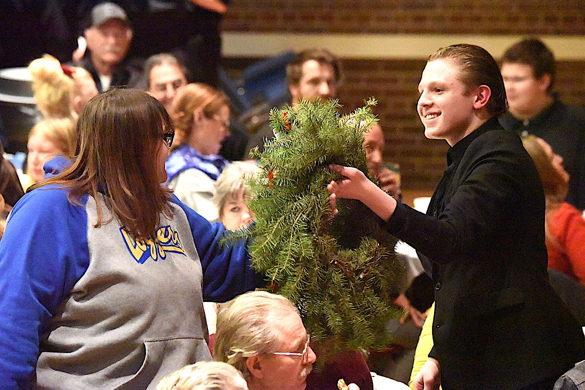 Libby High School band member Holden Cooper presents a Christmas wreath filled with lottery tickets to Brittany McMillan during the Dessert Concert Tuesday, Dec. 10, 2024, at the Memorial Center. (Scott Shindledecker/The Western News)