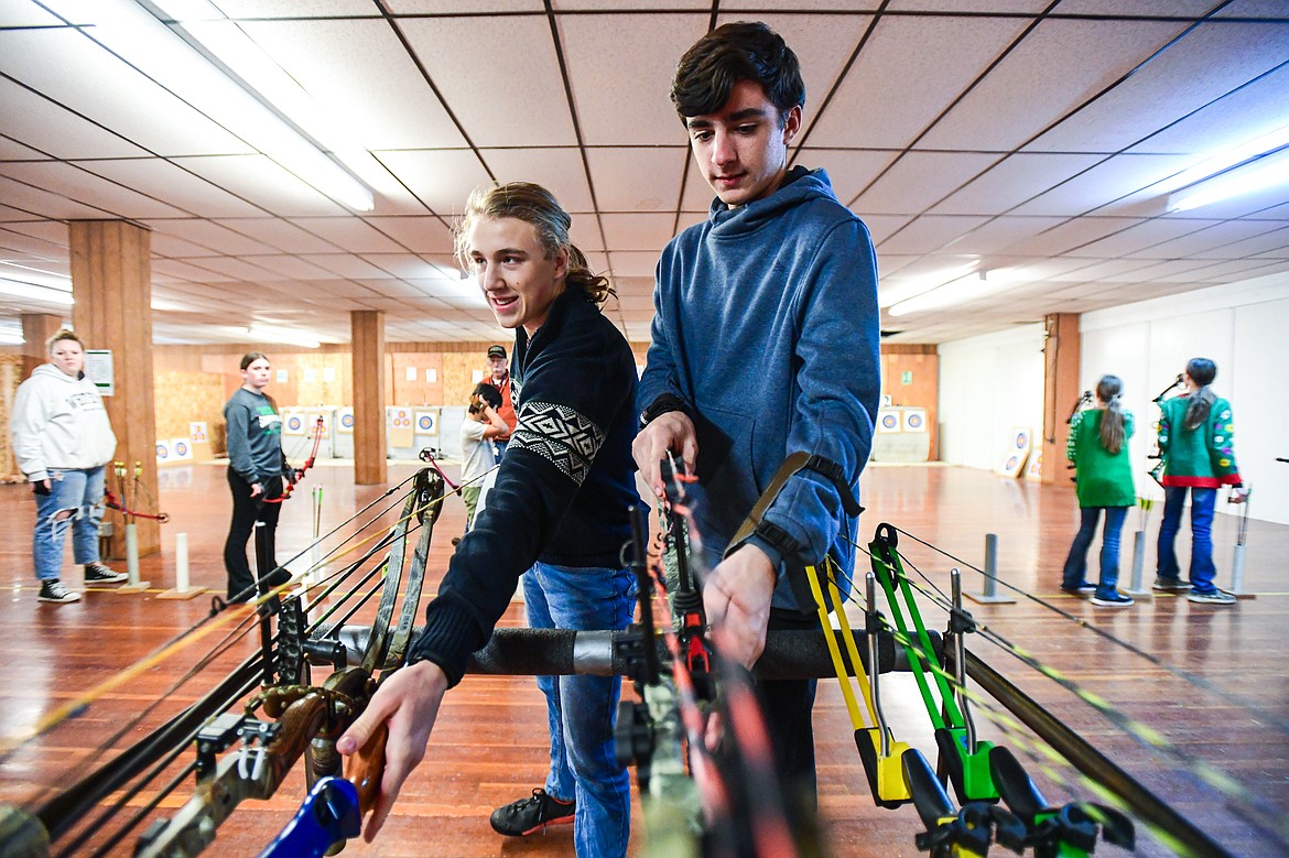 Jubal Bradley, left, and Jubal Clark take their bows off the rack in between rounds of archery practice with Flathead 4-H Shooting Sports on Thursday, Dec. 12. (Casey Kreider/Daily Inter Lake)