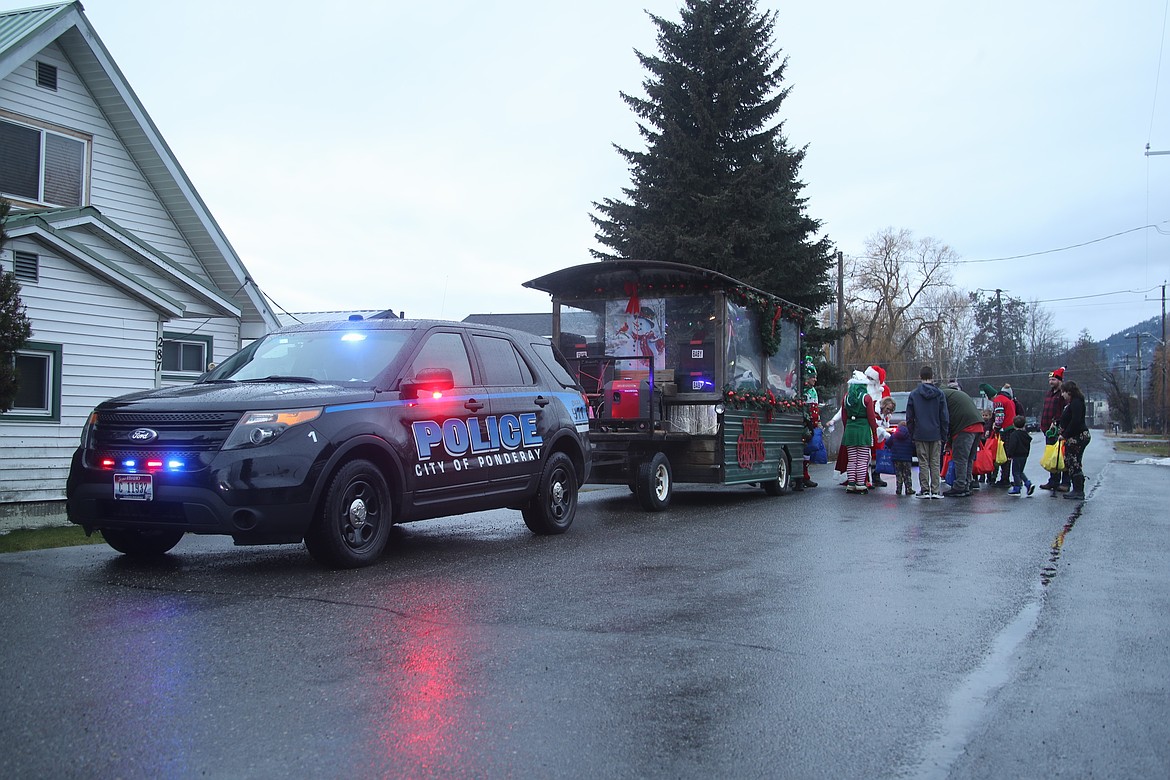 Residents gather around Ponderay's "Santa trolley" to receive gift bags from city staff and volunteers.