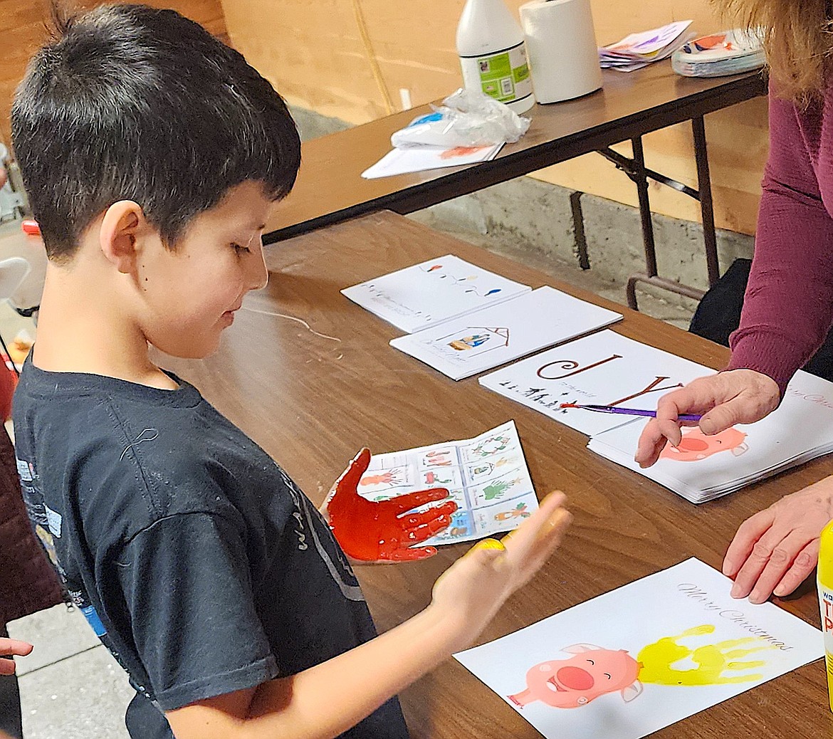 Activities for kids at Lights Under the Big Sky were grouped in the Horticulture Barn. One craft was using painted hands to make reindeer antlers, and this young man has one red hand and one yellow hand. (Berl Tiskus/Leader)