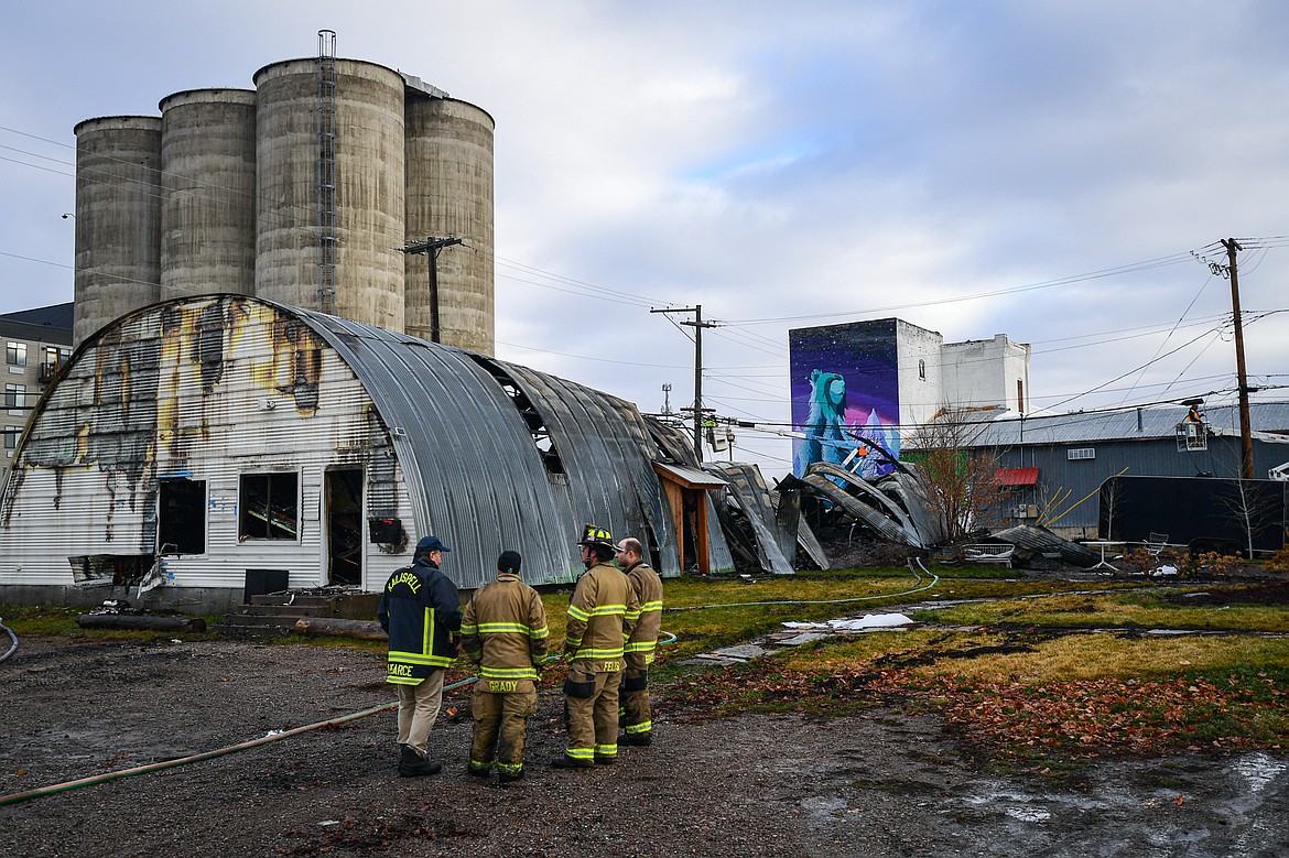 Kalispell Fire Department firefighters and fire chief Dan Pierce stand at the scene at the scene of an early-morning fire in a commercial structure along West Center Street in Kalispell on Tuesday, Dec. 17. (Casey Kreider/Daily Inter Lake)