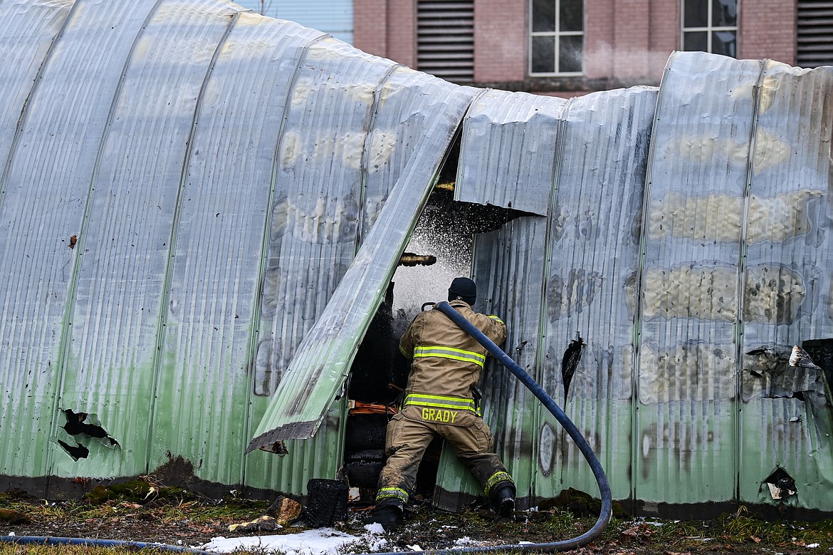 A Kalispell Fire Department firefighter sprays a hot spot at the scene of an early-morning fire in a commercial structure along West Center Street in Kalispell on Tuesday, Dec. 17. (Casey Kreider/Daily Inter Lake)