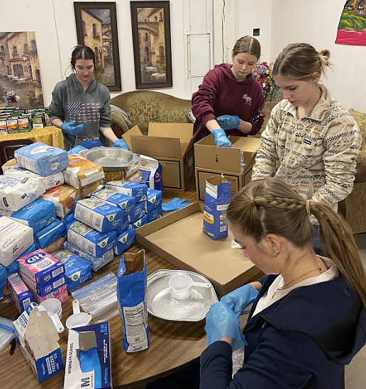 From left, Timberlake High School students Ashtyn Vanderpool, Lillie Nelson, Sierra Marosi and Jozee McArthur fill boxes with bags of sugar, flour and other baking staples Dec. 17 at the Church of the Solid Rock. Timberlake students worked with the Spirit Lake Community Coalition to fill food boxes for families in need.