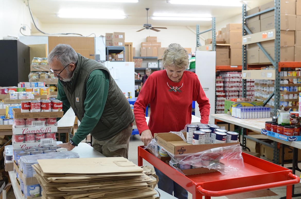 Paul and Sandi Fors were organized canned goods at Polson Loaves and Fish before filling Christmas bags and boxes with extra goodies for the holidays. (Kristi Niemeyer/Leader)