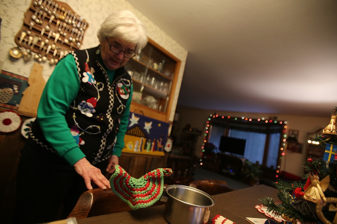 Ginger Wright demonstrates how some potholders are made to hold hot pot handles Friday afternoon in her festively decorated dining room.