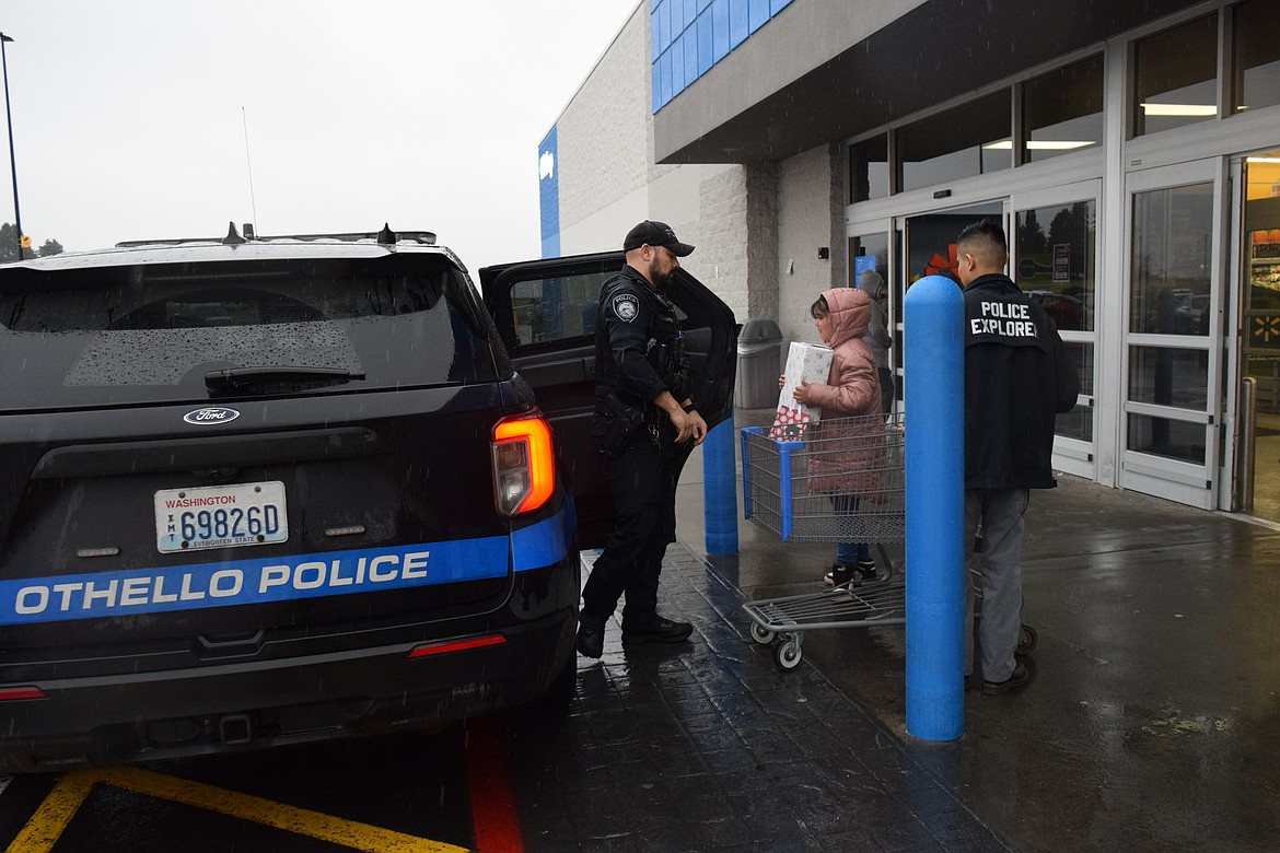 Othello Police Department officer Fernando Lopez and Elisa load her presents into the police vehicle after completing the Shop with a Cop on Saturday.