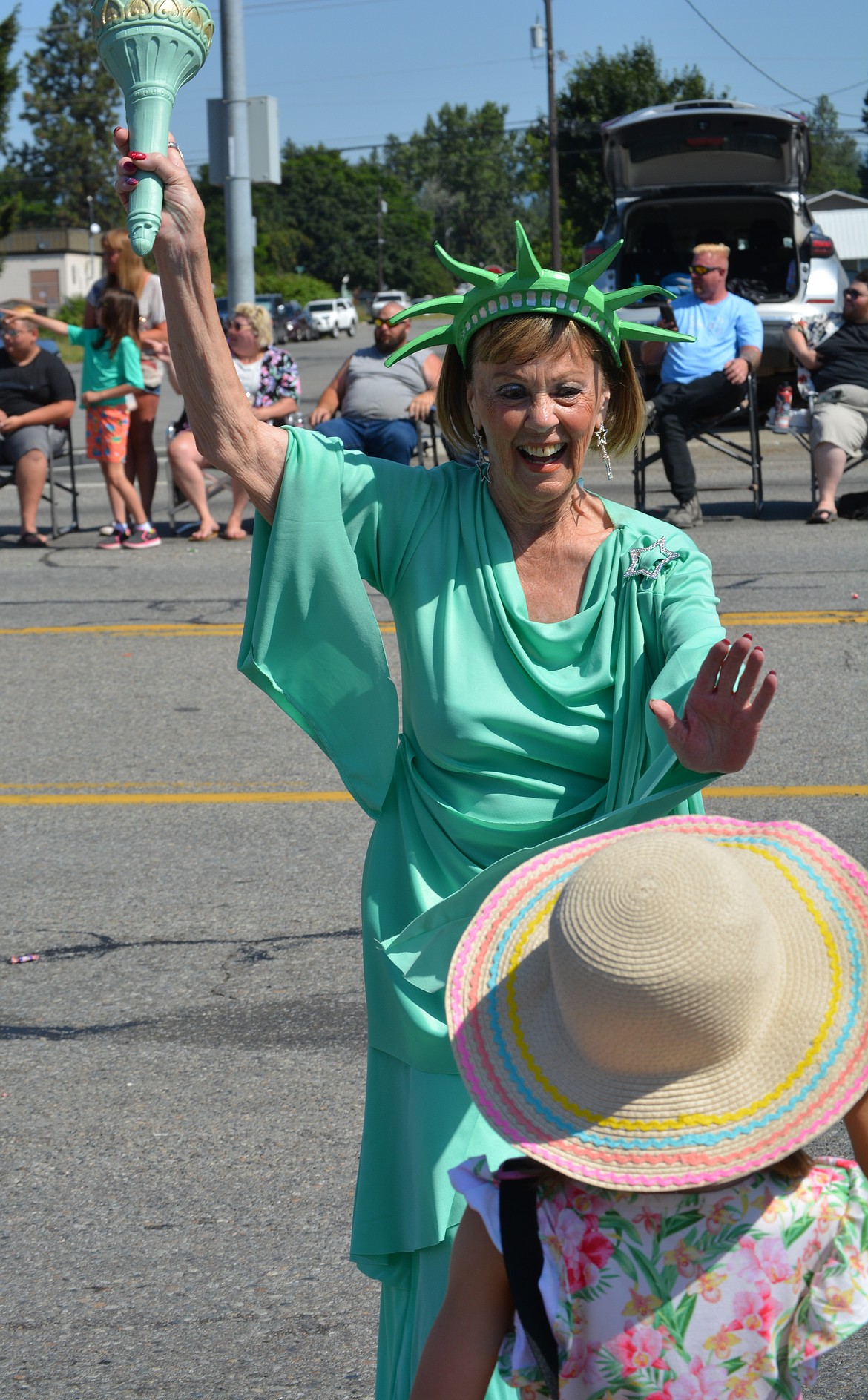 Abbi Young gets a high five from Lady Liberty as the North Idaho Sparklers pass by on Seltice Way during the Post Falls parade.