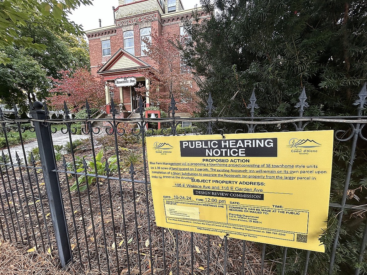 A sign regarding a public hearing on a proposed development for the Roosevelt Inn hangs on the property's fence.