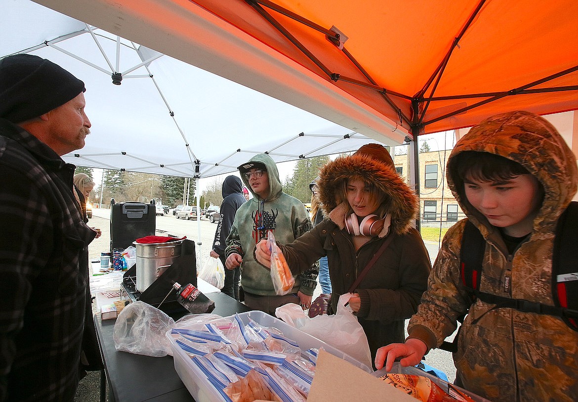 Mountain View seventh grader Evelynn Brekke selects a sandwich from the offerings in February while eighth grader Danny Desens, right, peruses snacks and eighth grader Khonner Peck, left, chats with Outreach Eats co-founder Garry Mickelson.