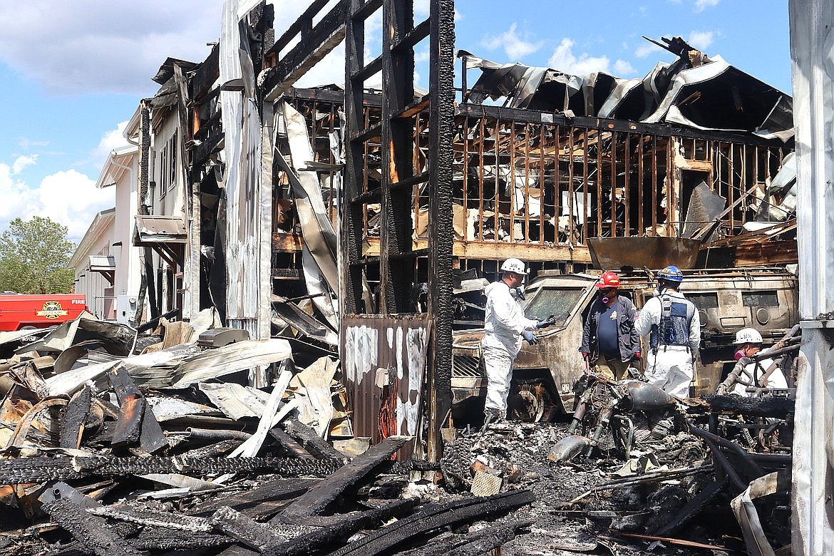 Investigators on Monday look over the remains of a Coeur d'Alene police building filled with vehicles and equipment that was destroyed in a fire.