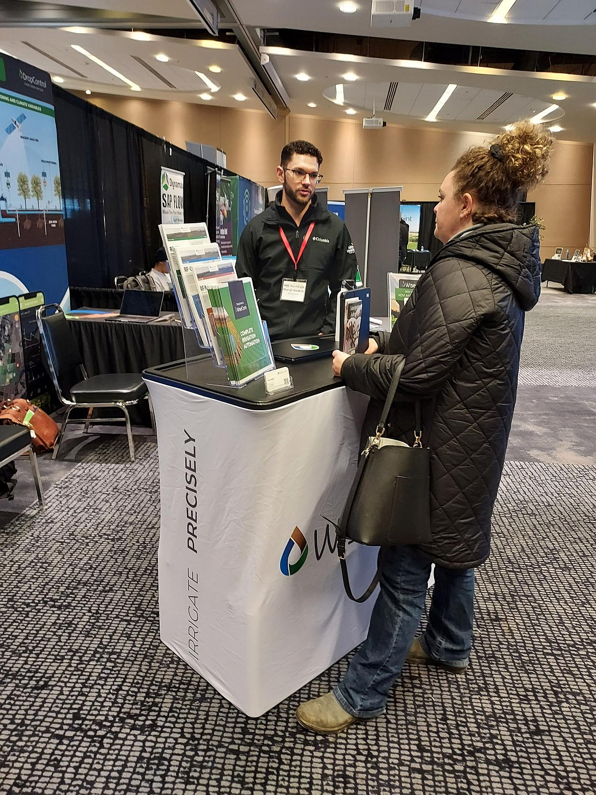 Darryl Hadlich of Wiseconn Engineering talks with a customer at the company booth at the Washington State Tree Fruit Association annual meeting Dec. 11.