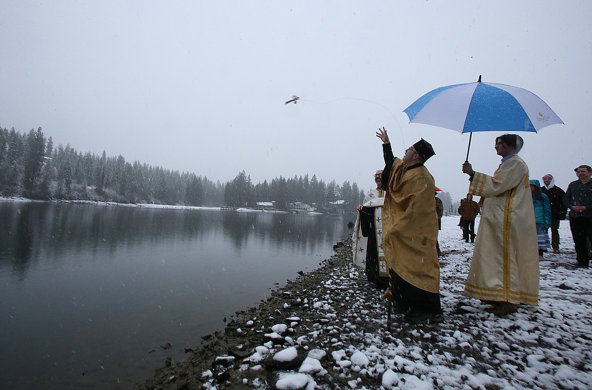 The Rev. Mark Townsend of St. John the Baptist Antiochian Orthodox Church in Post Falls tosses a cross into the Spokane River to bless the waters during a Theophany ceremony at a Post Falls home in January 2024.